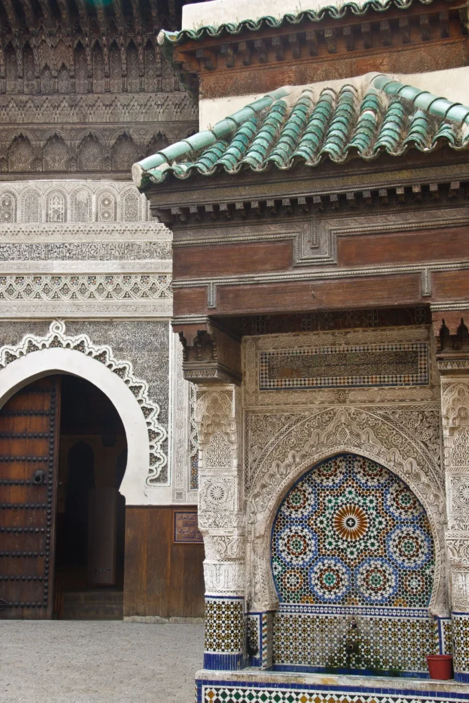 Portale del museo Nejjarine a Fes con tettoia in legno di cedro e fontana di zellige in primo piano