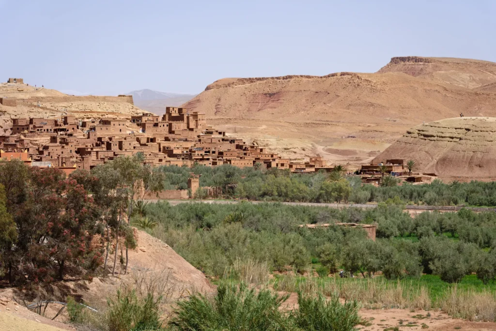 Villaggio fortificato in terra cruda di Ait Benhaddou sopra un palmeto verde, colline aride sullo sfondo