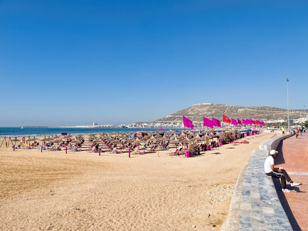 Longue plage de sable d'Agadir bordée d'immeubles blancs, avec la baie et l'océan Atlantique en arrière-plan